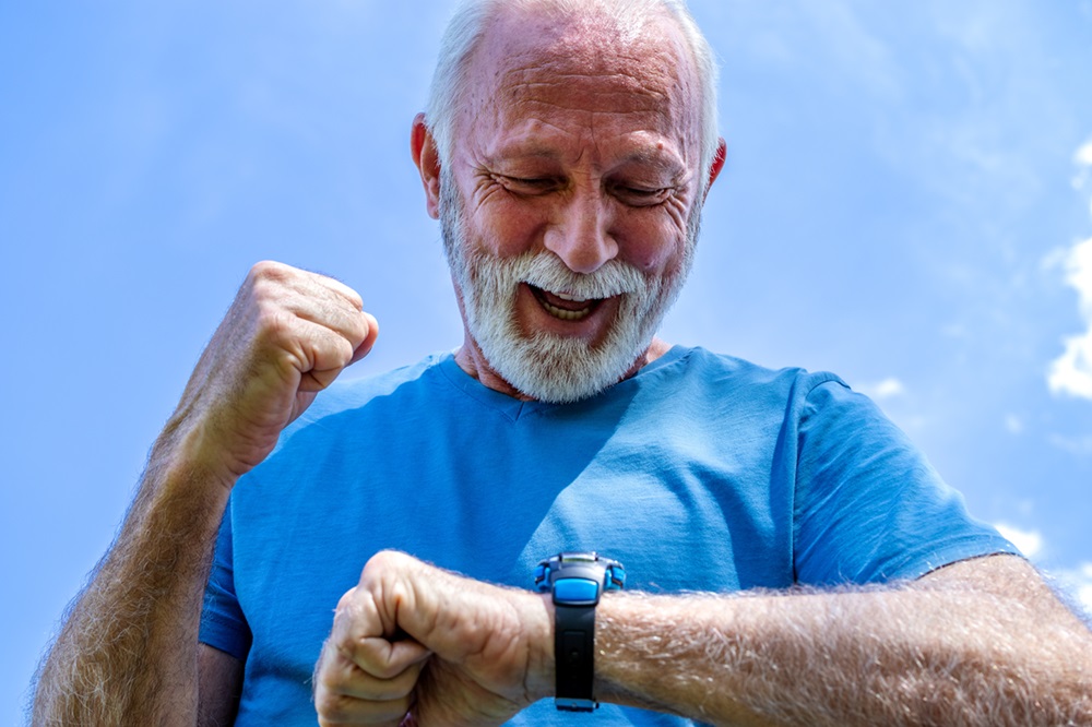 Anciano mirando su reloj inteligente de teleasistencia con función SOS en la muñeca